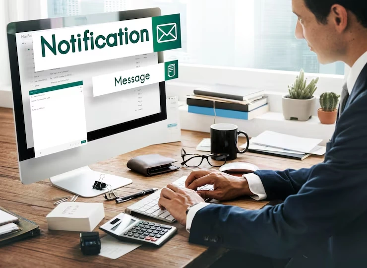 Business professional reviewing financing notifications on computer screen while working with calculator and documents