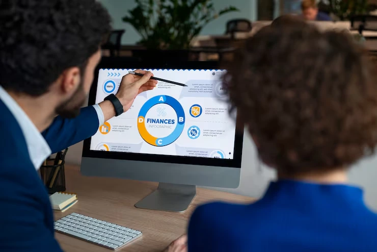 Two professionals reviewing financial charts and market data on computer screen during consultation