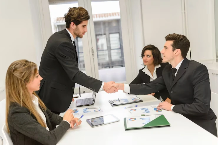 Business professionals shaking hands over property documents during successful negotiation meeting