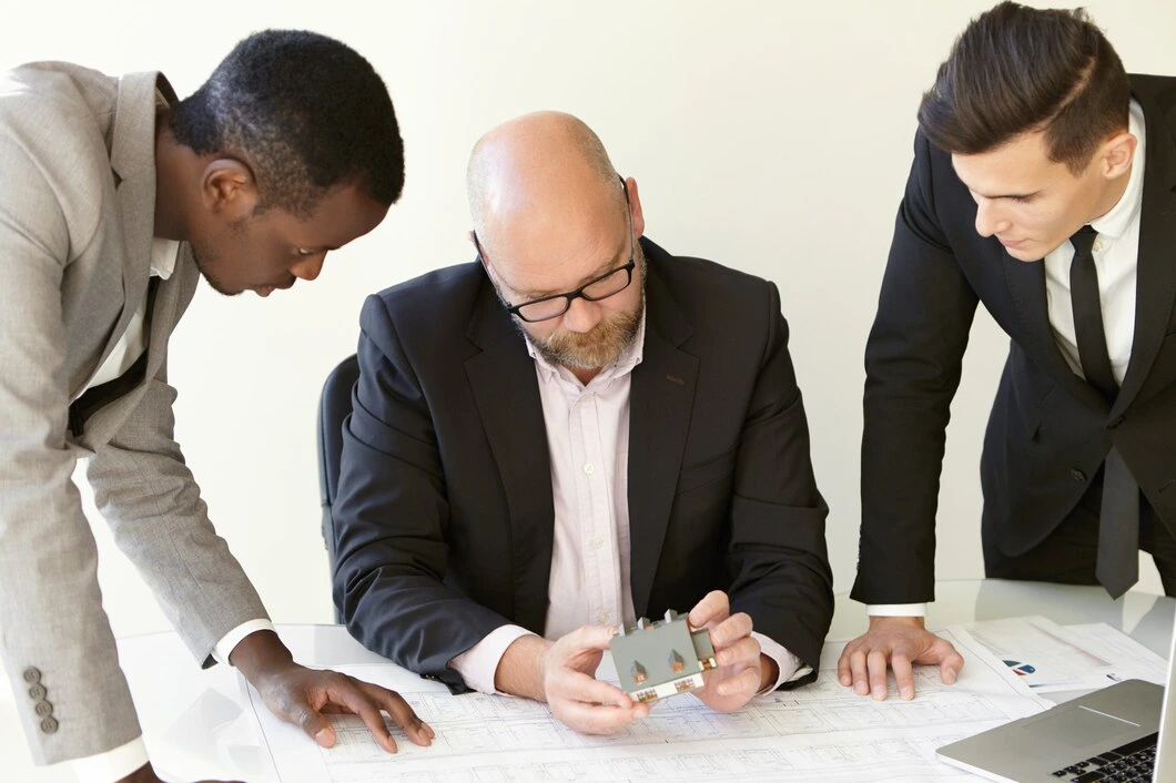 Three property managers collaborating over documents and property plans during management consultation